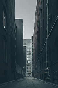man walking between tall buildings taken during daytime thumbnail
