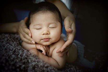 baby wears gray bottoms sleeping on brown textil thumbnail