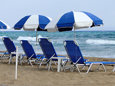 sun loungers with umbrellas on seashore thumbnail