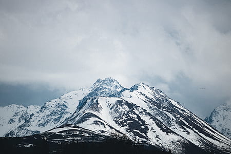 mountain range covered by snow under cloudy sky during daytime thumbnail