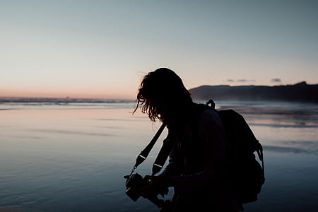 silhouette of man playing guitar on shoreline during golden hour thumbnail
