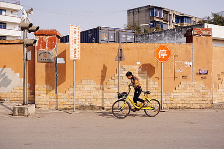 boy riding bike near brown bricked wall thumbnail