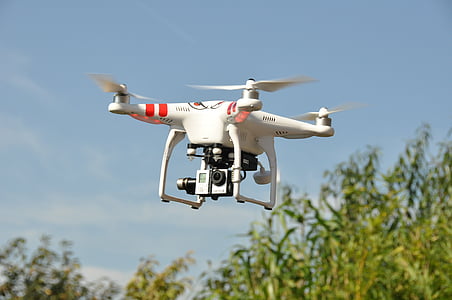 red and white DJi Phantom drone hovering on sky near tree during day thumbnail