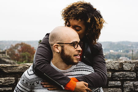 couple standing in front of gray wall bricks during daytime thumbnail