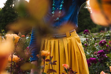 woman wearing brown pleated skirt and blue top thumbnail