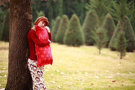 woman embracing pillow leaning on tree thumbnail