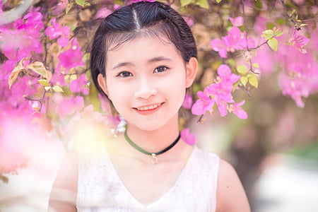 girl in white sleeveless top near pink petaled flowers thumbnail