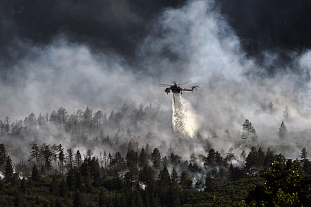 black chopper dropping water on forest fire thumbnail