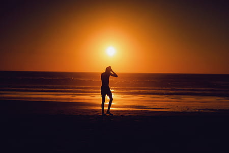 silhouette of man walking on shoreline golden hour photography thumbnail