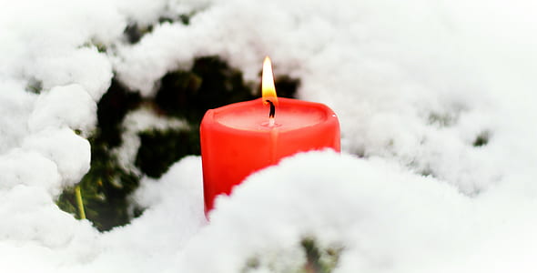 lighted red pillar candle near white snow thumbnail