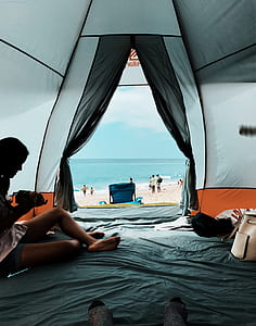 woman sitting inside tent near seashore thumbnail