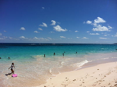 girl carrying pink bodyboard on seashore during daytime thumbnail