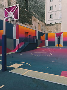 multicolored basketball court between white concrete buildings during daytime thumbnail