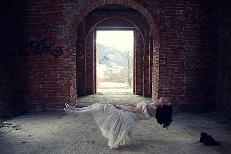woman in white dress floating inside red brick building at daytime thumbnail