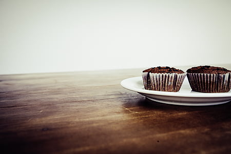 two chocolate cupcakes in white plate on brown table thumbnail