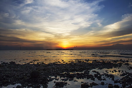 stone near shoreline under cloudy sky thumbnail