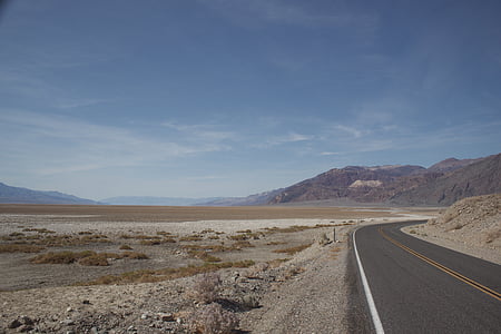 gray asphalt road surrounded by sand during daytime thumbnail