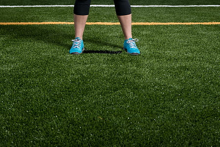 person wearing blue lace-up running shoes standing on green grasses thumbnail
