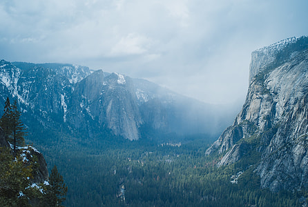 green trees surrounding snow coated mountains thumbnail