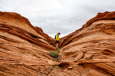 photo of man wearing yellow jacket in between rock formation thumbnail