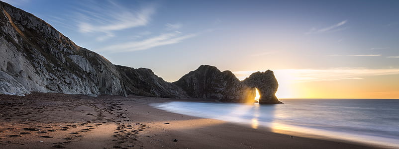 seashore with grey mountains during golden hor thumbnail