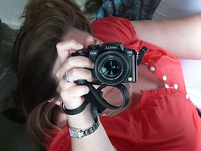 woman holding black Lumix DSLR camera thumbnail