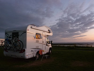 white RV parked near calm body water under white clouds thumbnail