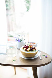 sliced fruit on white saucer besides footless wine glass on brown wooden table thumbnail
