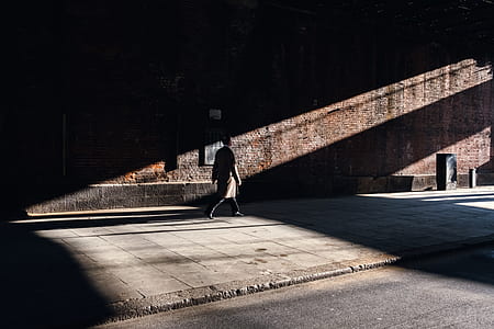 person walking beside brick wall thumbnail