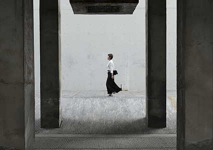 woman in white and black long-sleeved dress standing near wall during daytime thumbnail