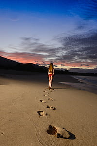 woman wearing red bikini walking on shoreline thumbnail