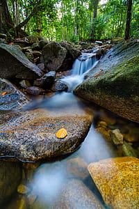 timelaps photography of running water on rocks surrounded trees thumbnail