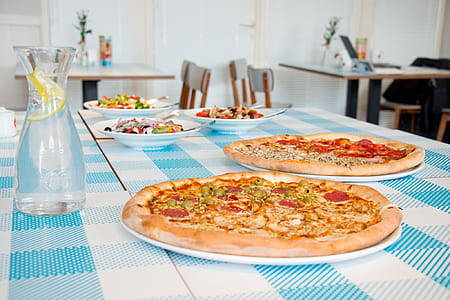 two assorted pizzas on table thumbnail