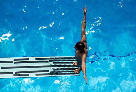 view of a man about to jump from a plank down to a pool thumbnail