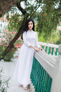 woman wearing white sari standing on tiled floor beside green and gray concrete handrail thumbnail