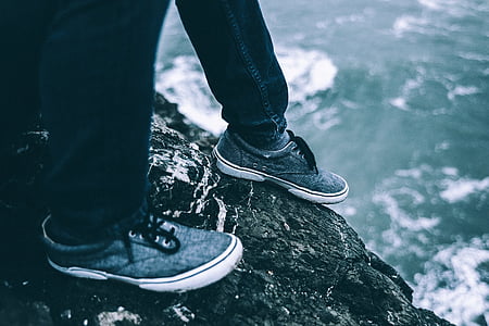 photo of person sitting on cliff beside body of water thumbnail