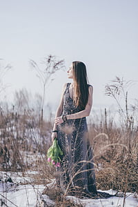 woman holding bouquet of flowers near brown grass at daytime thumbnail