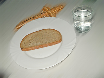 slice of bread on ceramic saucer beside drinking glass thumbnail