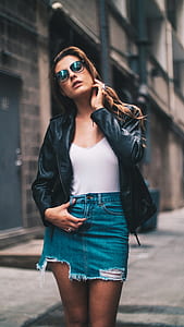 woman in black leather jacket near concrete building thumbnail