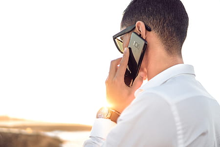 Shallow Focus Photography of a Man in White Collared Dress Shirt Talking to the Phone Using Black Android Smartphone thumbnail
