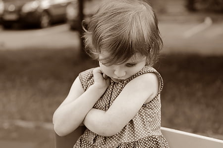 grayscale photo of girl wearing gray and white polka-dot sleeved dress with hand on cheek thumbnail