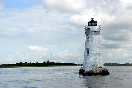 white lighthouse surrounded by body of water thumbnail