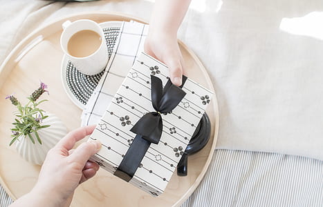 two people's hands holding white and black gift box thumbnail