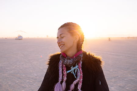 woman wearing black jacket walking on gray sand during daytime thumbnail