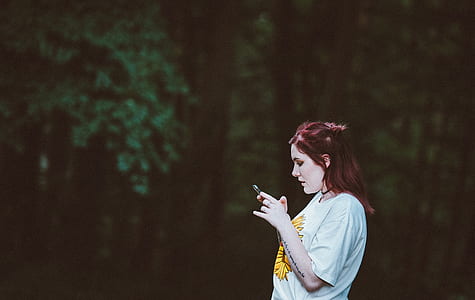 woman using smartphone while standing in the forest thumbnail