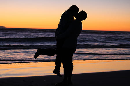 silhouette of kissing coupe near shore of sea during golden hour thumbnail