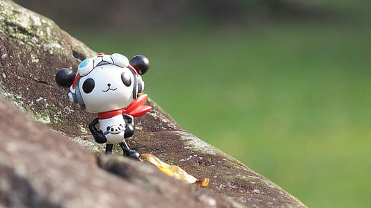 white and black panda plastic toy figure on rock thumbnail