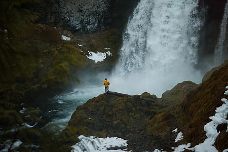 person standing near waterfalls thumbnail