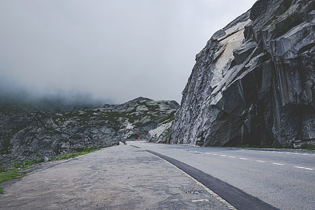 empty concrete road beside rock cliff thumbnail