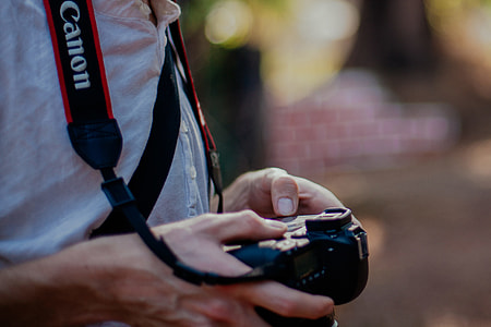 person holding black Canon DSLR camera shallow focus photography thumbnail